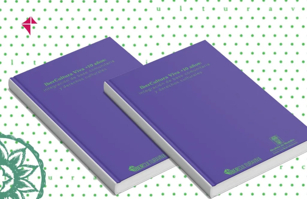 Foto de 2 ejemplares, con tapa morada, del libro IberCultura Viva + 10 años: integración de base comunitaria y derechos culturales.